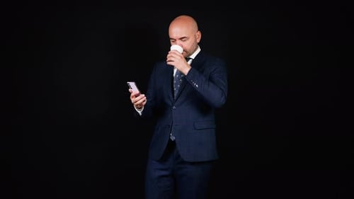 Man in Suit Drinks Coffee and Uses Phone