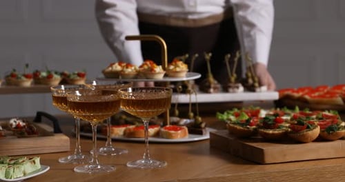 Waiter arranging appetizers for buffet at table, closeup