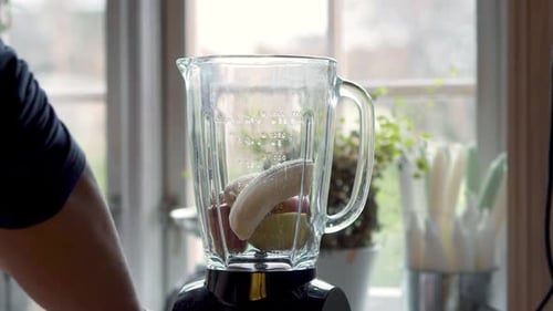 Person putting healthy ingredients into a blender to mix a healthy smoothie.