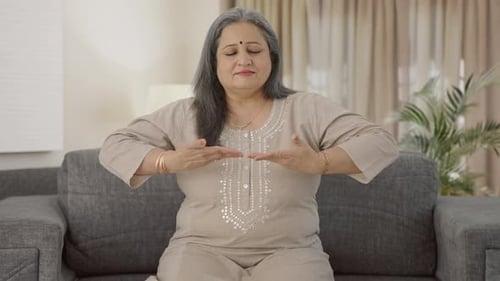 Woman Practicing Calming Meditation on Couch Indoors