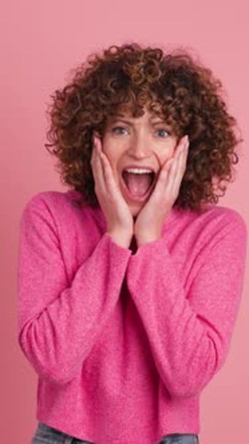 Woman Expressing Shock and Clapping on Pink Background