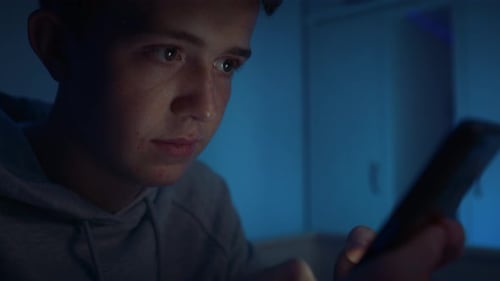 Teen Using Smartphone Indoors at Night