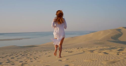 Beautiful Woman Runing in Long White Clothes Against the Backdrop of a Beautiful Sunset on Sand Dune