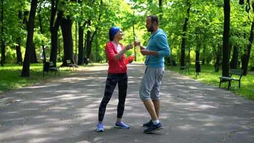 Couple drinking electrolytes after run in the park