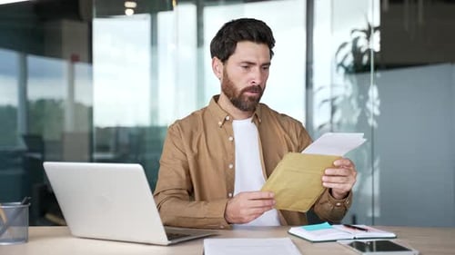 Worried Man Reading Documents at Office Desk