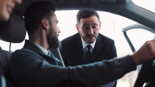 Seller of Prestigious Car Dealership Telling Characteristics of Vehicle Potential Buyers Listening