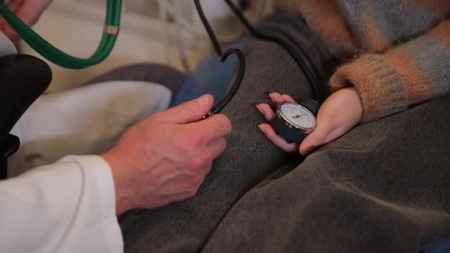 El médico examina a la niña midiendo la presión arterial con un tonómetro clínico (médico de familia)