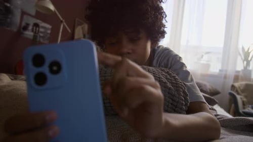 Boy with Mobile Phone Lying in Bed