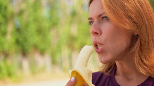 Woman Eating a Banana Outdoors in Close-Up