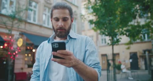 Man Smiling Using Smartphone on Urban Street