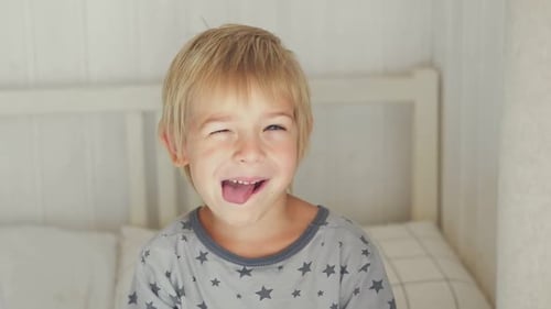 5 Jahre Junge scherzt, streckt mit albernem Gesichtsausdruck die Zunge raus, Kind macht Gesicht lustig, töricht