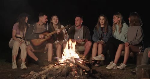 Young Adults Singing Around Campfire at Night