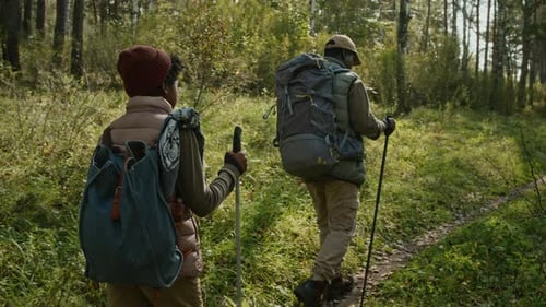 Dad and Son Walking down Path with Hiking Sticks Spending Weekend Outdoors