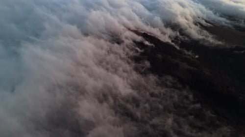 Aerial View of Clouds Rolling Over Mountains at Golden Sunset