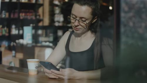 Close Up of Woman Holding Cell Telephone Watching Video on Mobile Phone During Coffee Break View