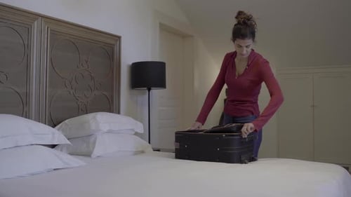 tired woman arriving at hotel room after long flight unpacking suitcase on bed