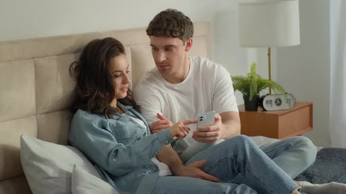 Young Couple Using Smartphone in Bedroom Together