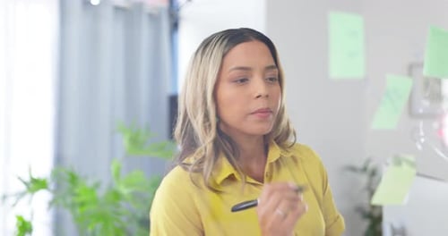 Woman Brainstorms Ideas Using Sticky Notes on Whiteboard