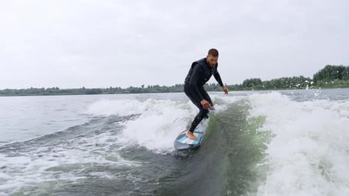 Man Wake Surfing on Lake in Black Wetsuit