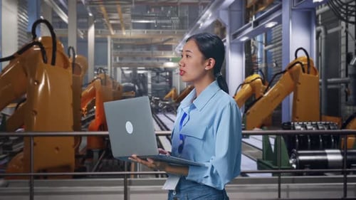 Woman Engineer with Laptop in Robotics Factory
