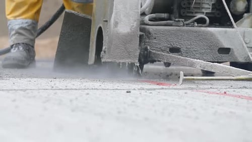Concrete saw and feet of road worker cutting asphalt