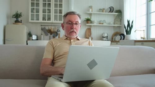 Man with Laptop on Couch in Home Setting