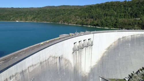 Drone tracking shot of a group of tourists visiting a dam in summertime