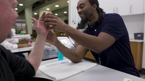 Fisioterapeuta examinando la mano de un paciente en un centro de rehabilitación de 30 a 34 años