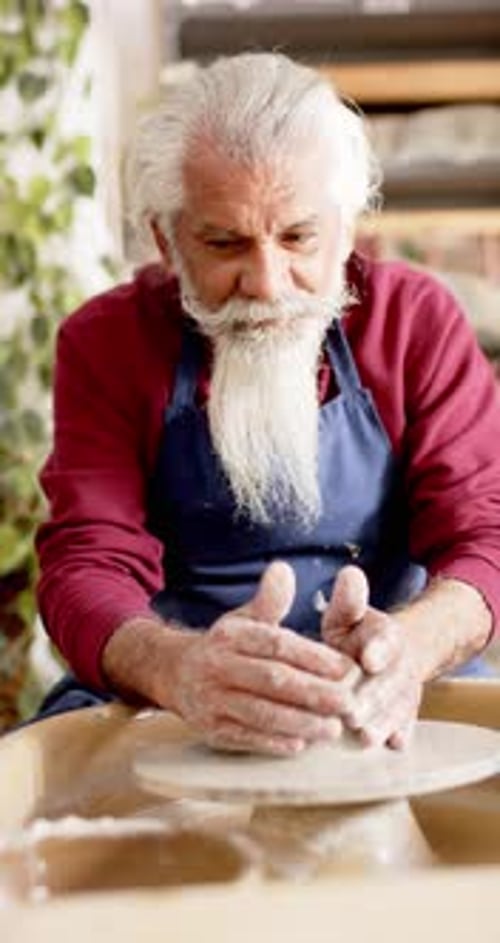 Potier masculin concentré avec une longue barbe utilisant un tour de potier dans un studio de poterie, Ralenti