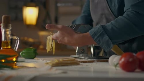 Adult Making Pasta with Pasta Machine in Kitchen
