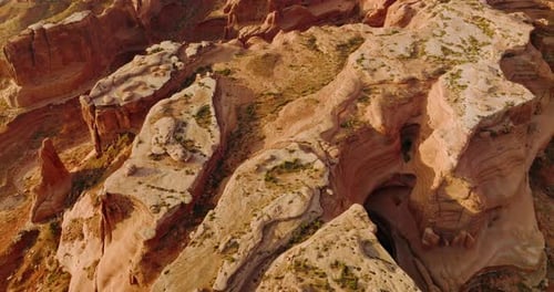 Unusual oddly-shaped red rocks of American canyons in Utah. Descending over a big rock