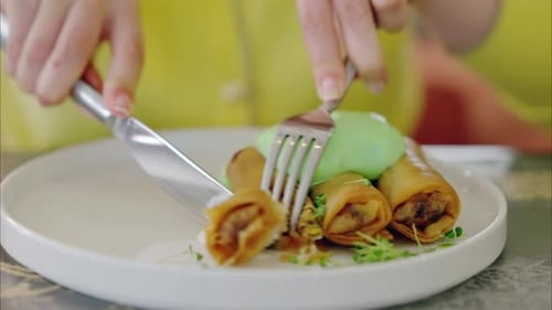 Close-up of woman eating spring rolls at a restaurant