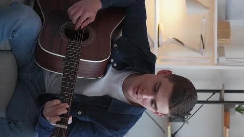 Young Adult Playing Acoustic Guitar at Home