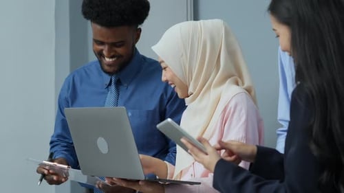 Smiling Colleagues Working Together at Laptop in Office