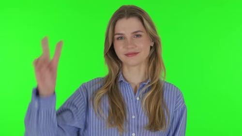 Portrait of Young Woman with Victory Sign on Green Background