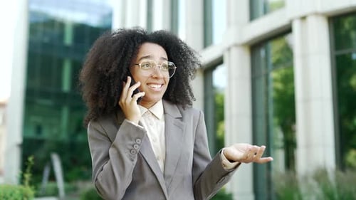 African American businesswoman talking on the phone outside modern office building. Professional