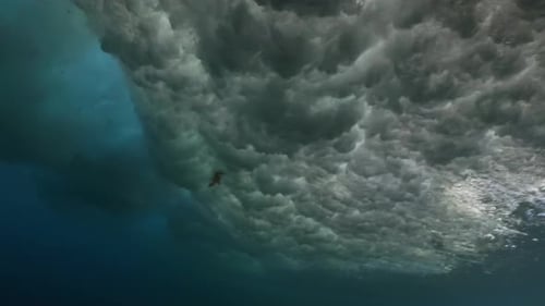 Plan panoramique sous-marin d'une grosse vague touchant la surface d'une mer aigue-marine.
