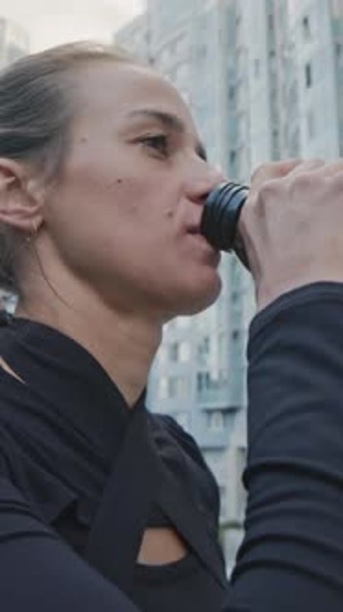 Woman Drinking from Reusable Water Bottle in City