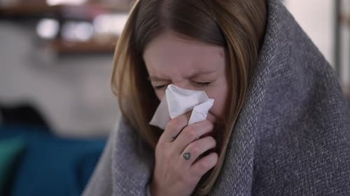Sick Woman Wrapped in Blanket Wiping Nose