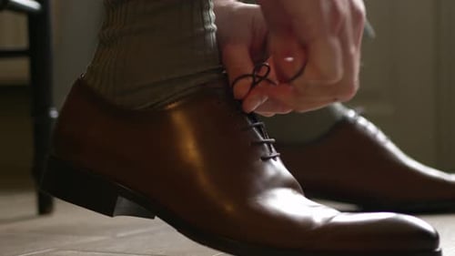 Cropped Hands Of A Man Tying The Lace Of A Classic Brown Shoe Leather. Close-up Shot