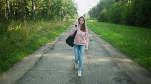 Sangle de sac pour jeune femme marchant sur une route forestière