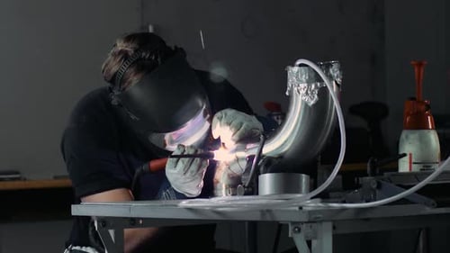 Welder Working on Metal Pipe in Workshop