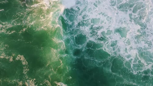 Stormy turquoise ocean waves rolling and splashing creating white foam bubbles