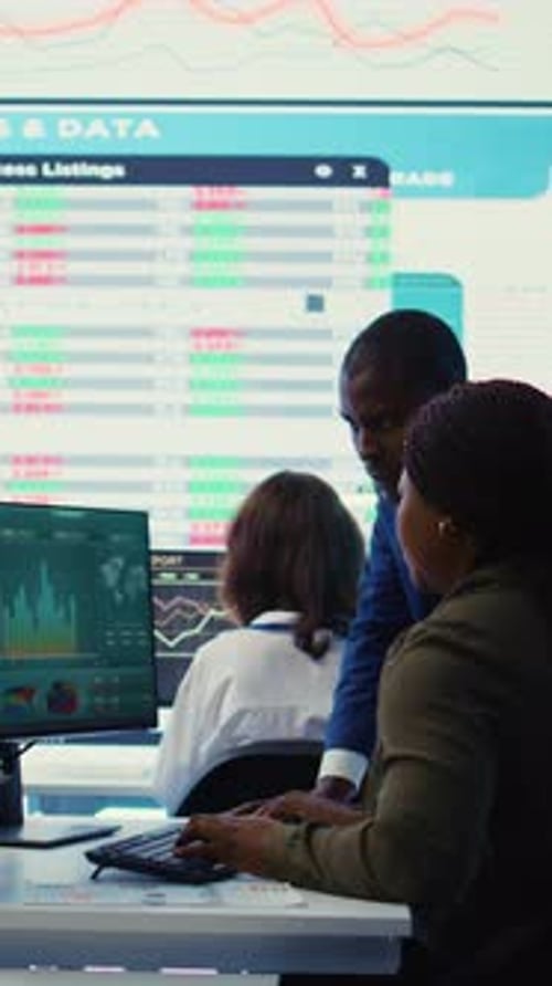 Vertical Video Financial Analyst Works on Resource Allocation Plans with His Staff