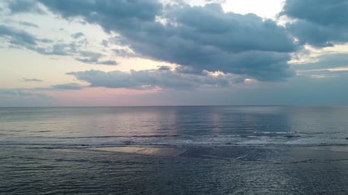 Bewölkter Sonnenuntergangsabend auf See mit ruhigen Wellen und Himmelsreflexionen im Wasser. Leichte Vorwärtsbewegung