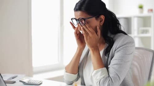 Woman Experiences Eye Strain while Working at Desk