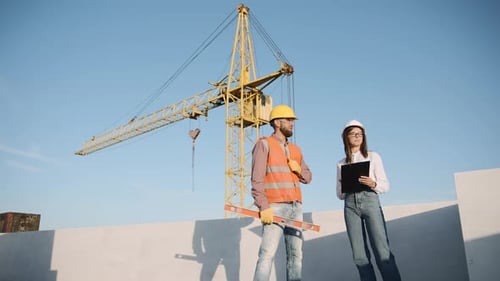 Das Bauteam bespricht den Projektfortschritt auf einer Baustelle mit Kran im Hintergrund