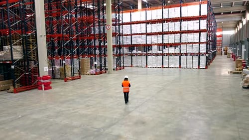 Logistics supervisor walking in large warehouse