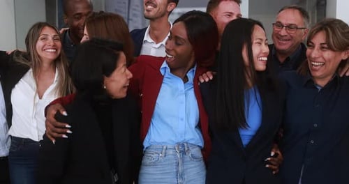 Un equipo empresarial multirracial se abraza para celebrar el éxito en una moderna oficina de EE. UU.