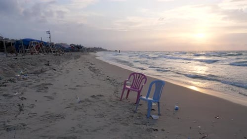 Two lone plastic chairs left on the beach amongst the devastation of war in Gaza